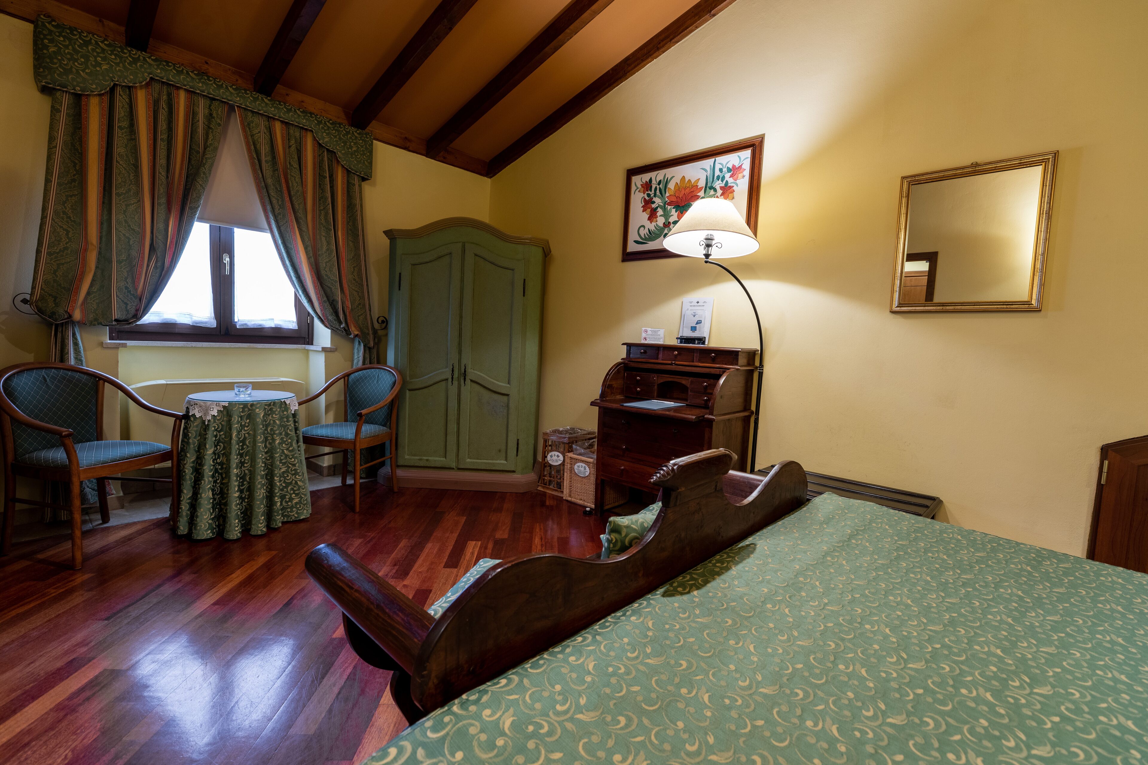 Una habitación con una cama, dos sillas, una mesa, una lámpara, un aparador y un armario.