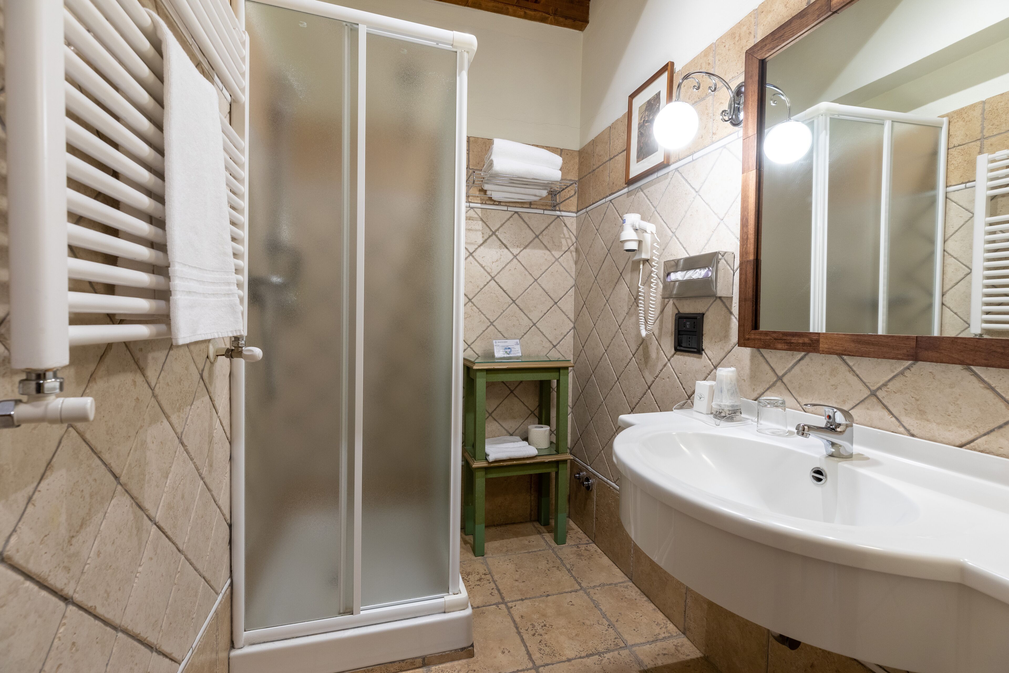 Un bagno con doccia vetrata, un lavandino e uno specchio.