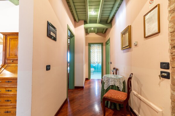 A narrow hallway with wooden floors, green doors, and a table with a lace tablecloth. - Relais Santa Anastasia (Castelbuono)
