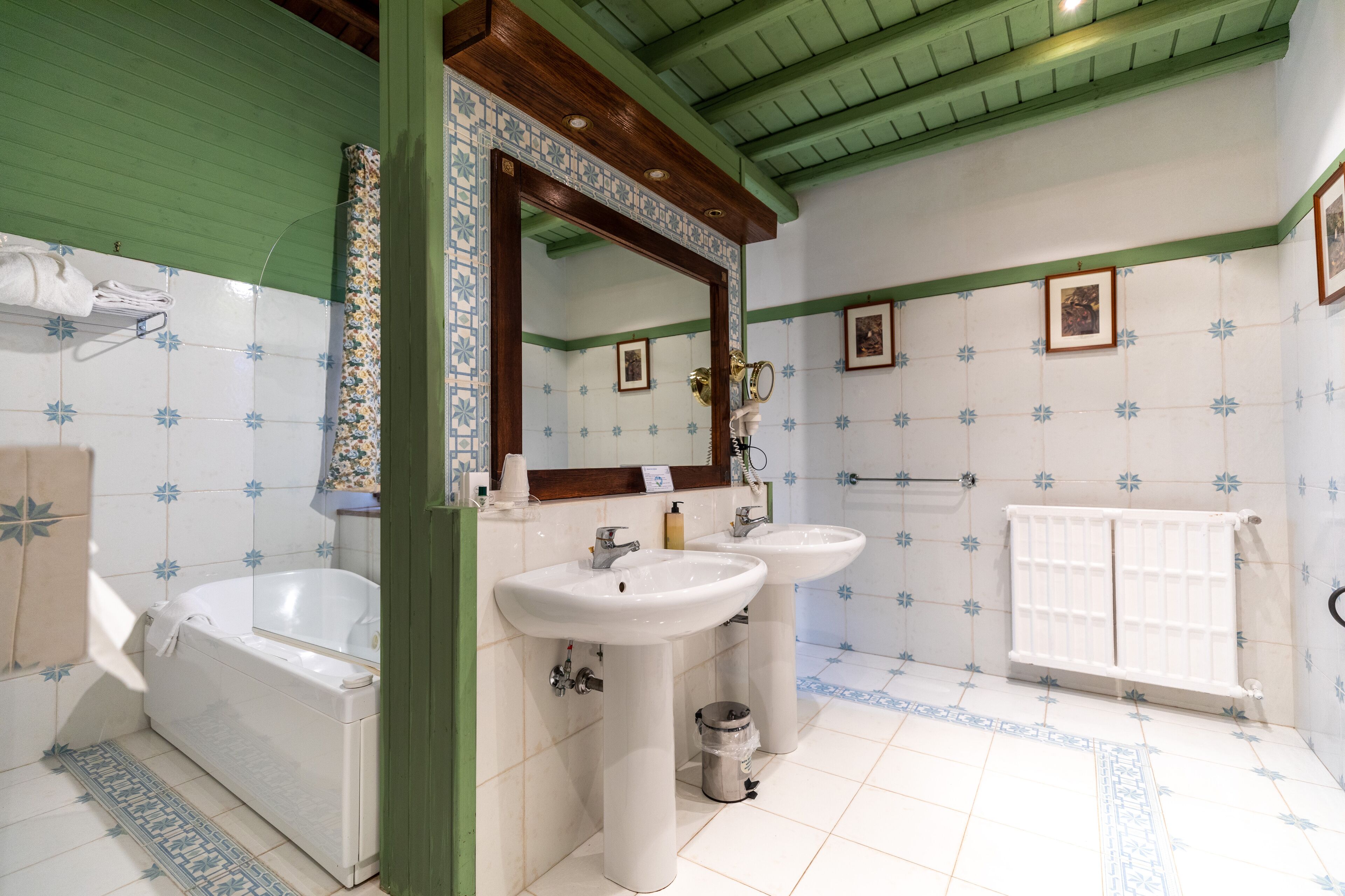 Un baño con dos lavamanos, una bañera y un espejo.