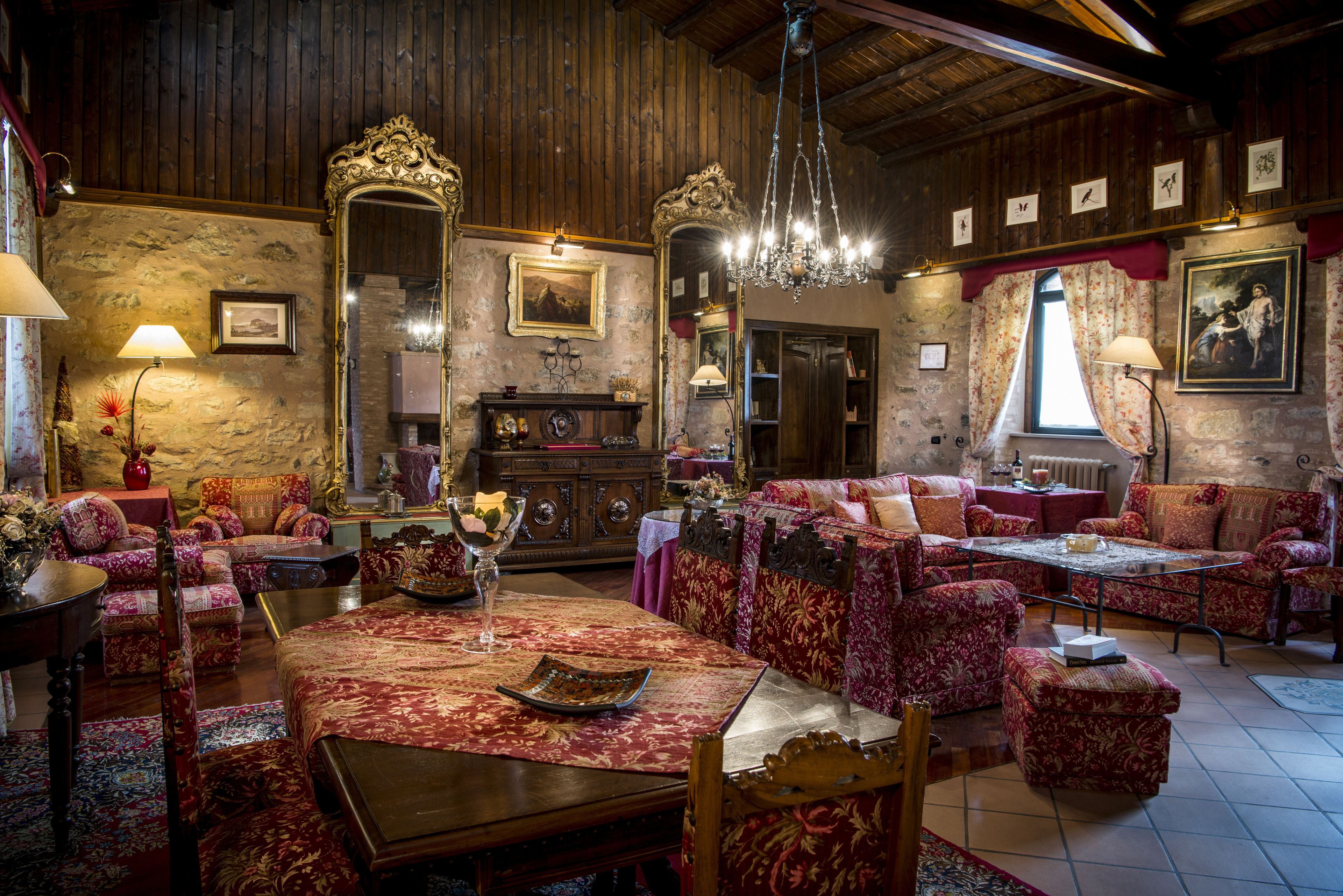 Une pièce de style traditionnel avec des murs et un plafond en bois, un lustre, une cheminée et un coin repas comprenant une table et des chaises.