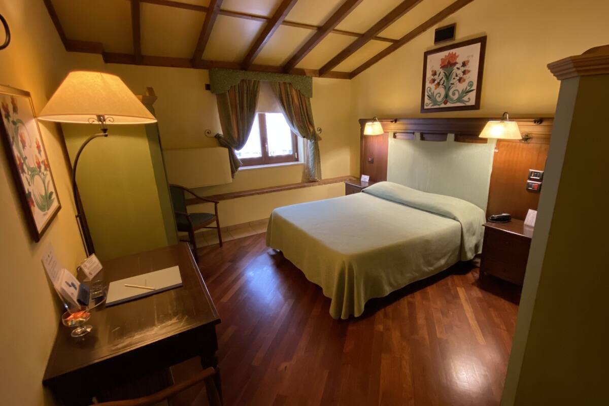 A room with a bed, desk, and lamps.