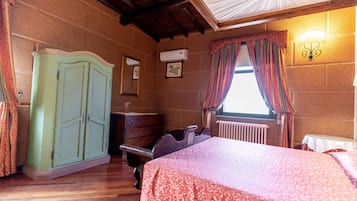 Un dormitorio con cama, cómoda, radiador y ventana con cortinas.