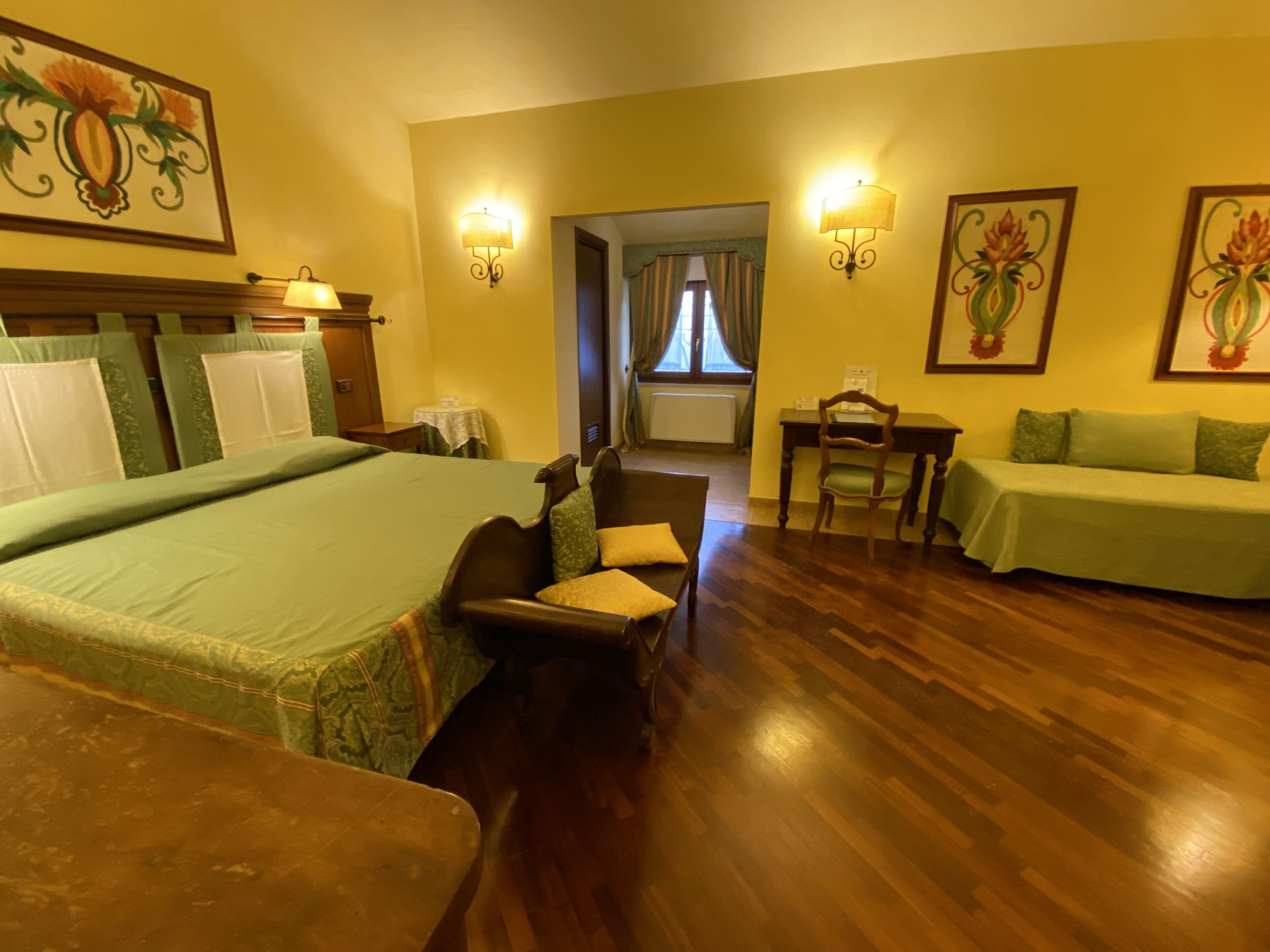 Een hotelkamer met een groot bed, een bureau, een stoel, een bank en twee wandlampen.