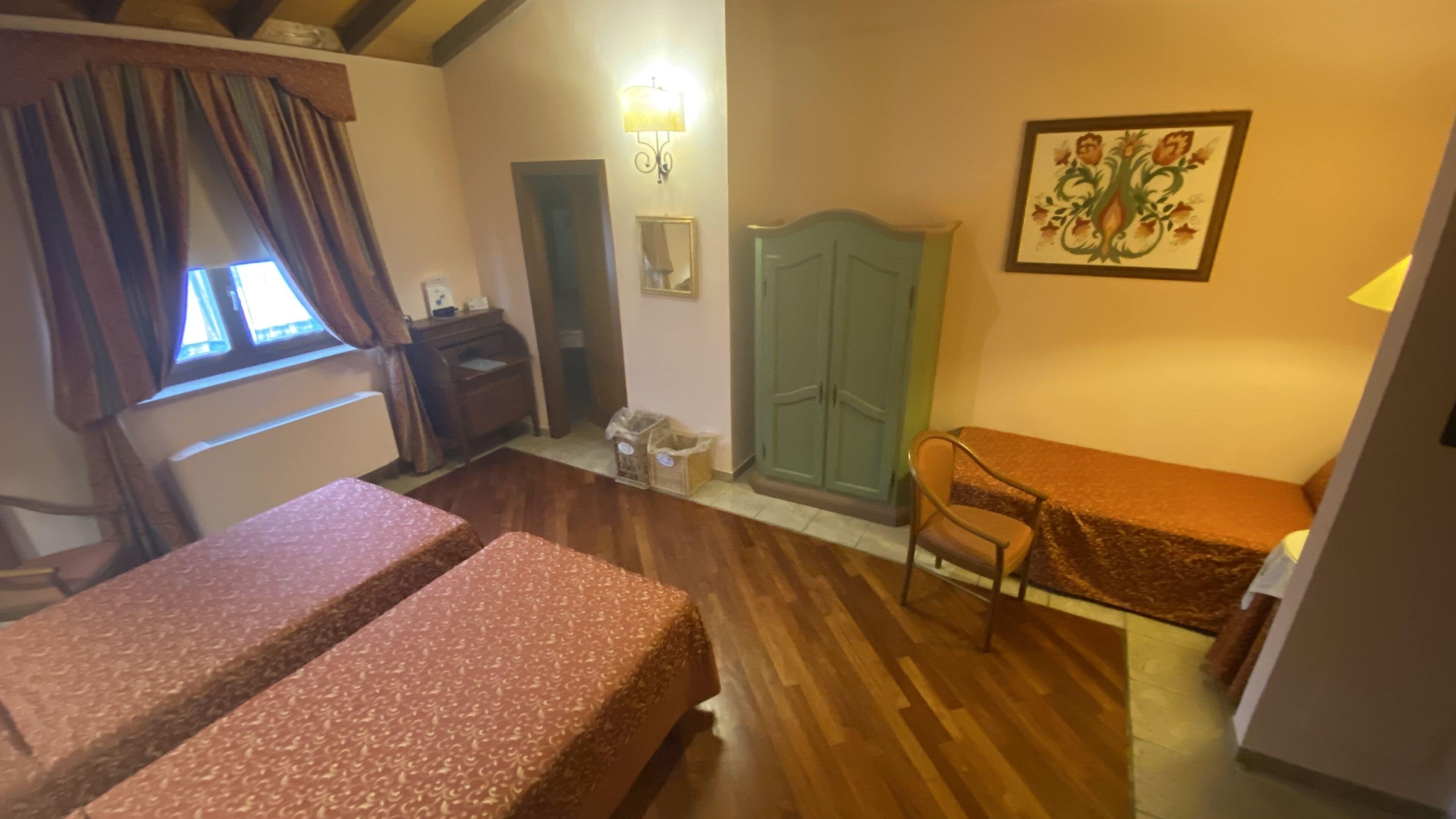 A room with two beds, a wardrobe, a desk, and a chair.