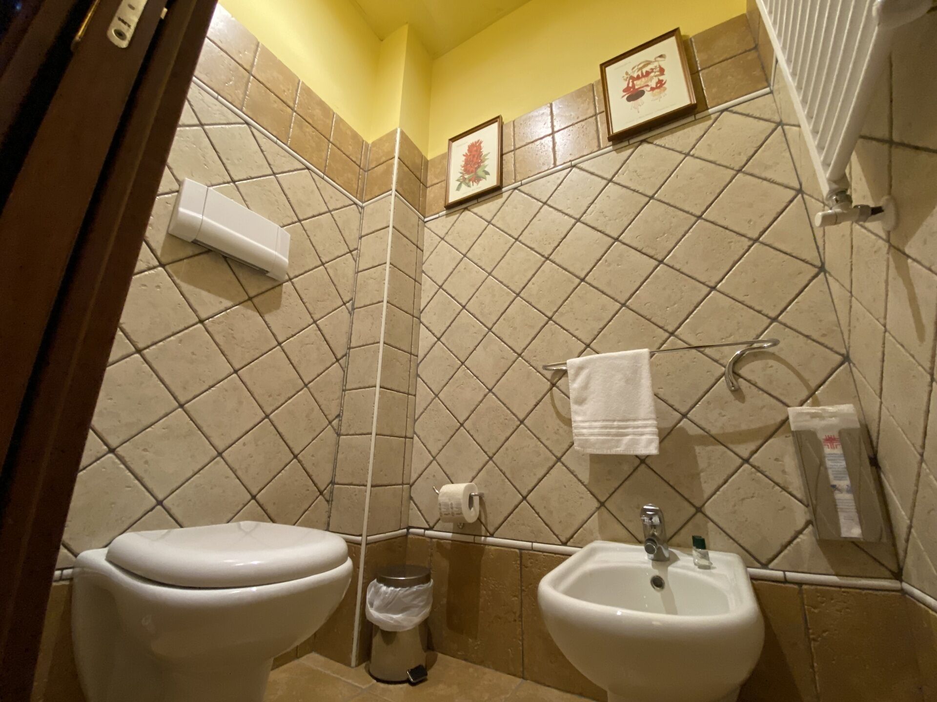 A bathroom with two sinks, a toilet, and a trash can.