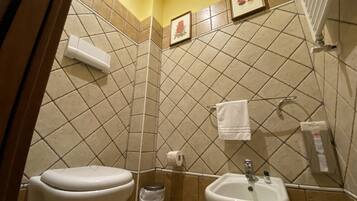 A bathroom with two sinks, a toilet, and a trash can.