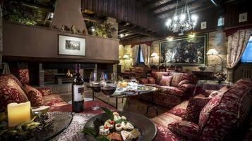Un salon chaleureux et bien éclairé, doté d’une cheminée, de sièges confortables et d’un coin repas avec une table mise pour le dîner.
