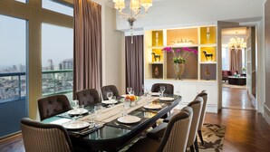 A dining area with a city view, a chandelier, and a decorative shelf with items. - Ascott Jakarta (Jakarta)
