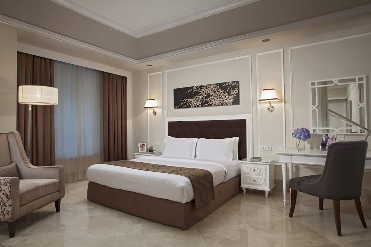 Una habitación de hotel con una cama grande, un escritorio, una silla y un espejo.