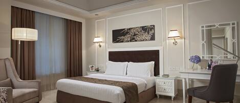 A hotel room with a large bed, a desk, a chair, and a mirror.