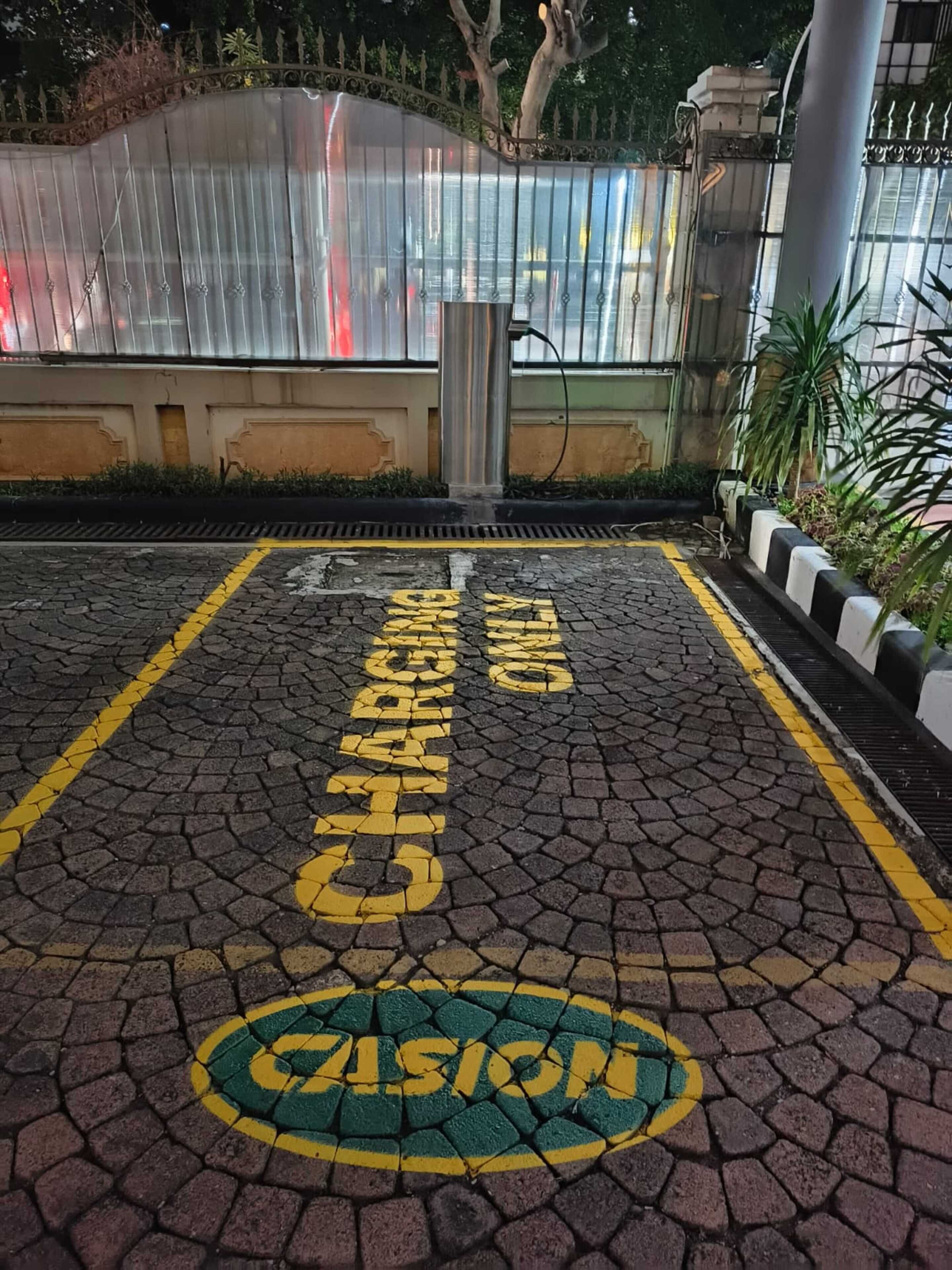 A paved area with yellow and green markings, including the words "CHARGING POINT" and "PARKING" in large letters.