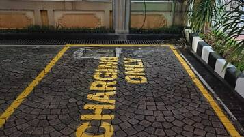 Una zona pavimentada con marcas amarillas y verdes, que incluye las palabras “CHARGING POINT” y “PARKING” en letras grandes.