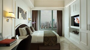 A hotel room with a large bed, a television, a desk with a book, and a city view. - Ascott Jakarta (Jakarta)
