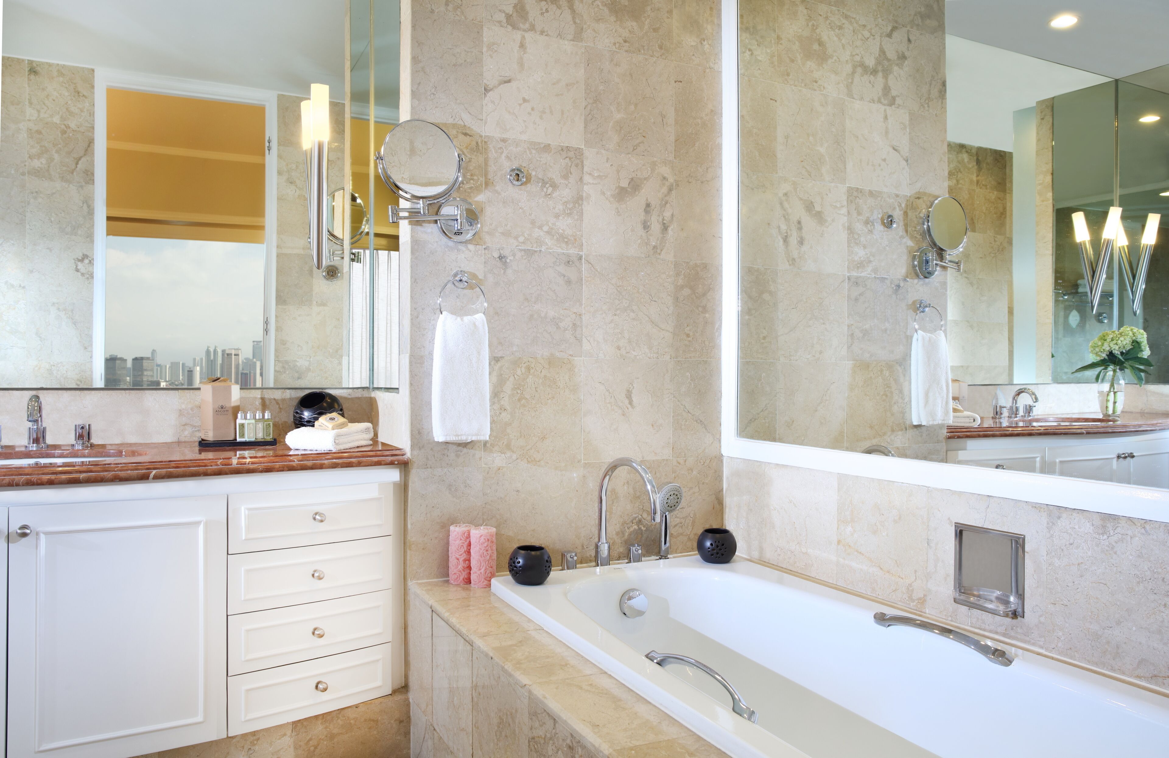 A modern bathroom with a large bathtub, double sinks, and a vanity with drawers.