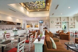 Eine moderne Hotellobby mit Essbereich, Sitzgelegenheiten und einer Küche im Hintergrund.