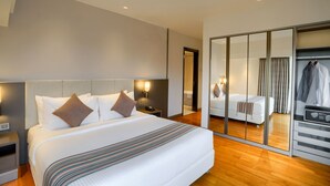 A hotel room with a large bed, a wardrobe, a mirror, and a nightstand with a lamp. - Somerset Berlian Jakarta (Jakarta)