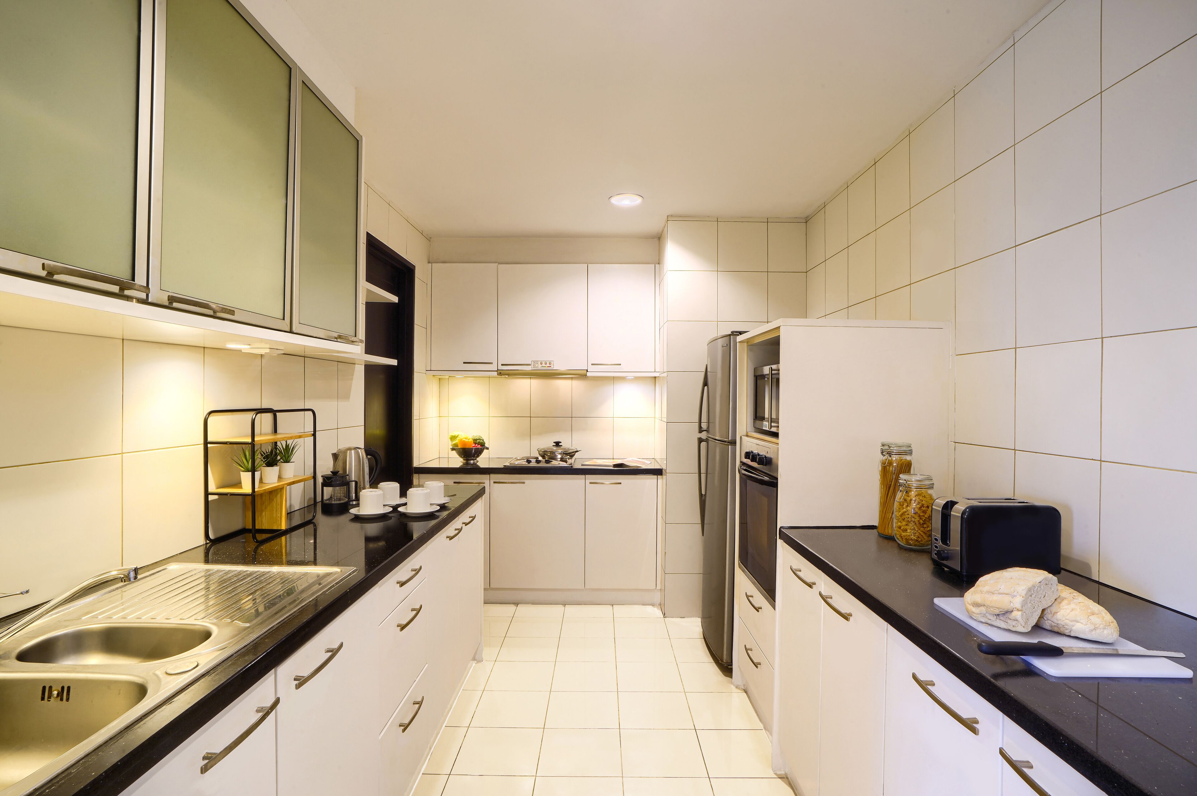 Een moderne keuken met witte kastjes, een roestvrijstalen spoelbak, een koelkast en een broodrooster.