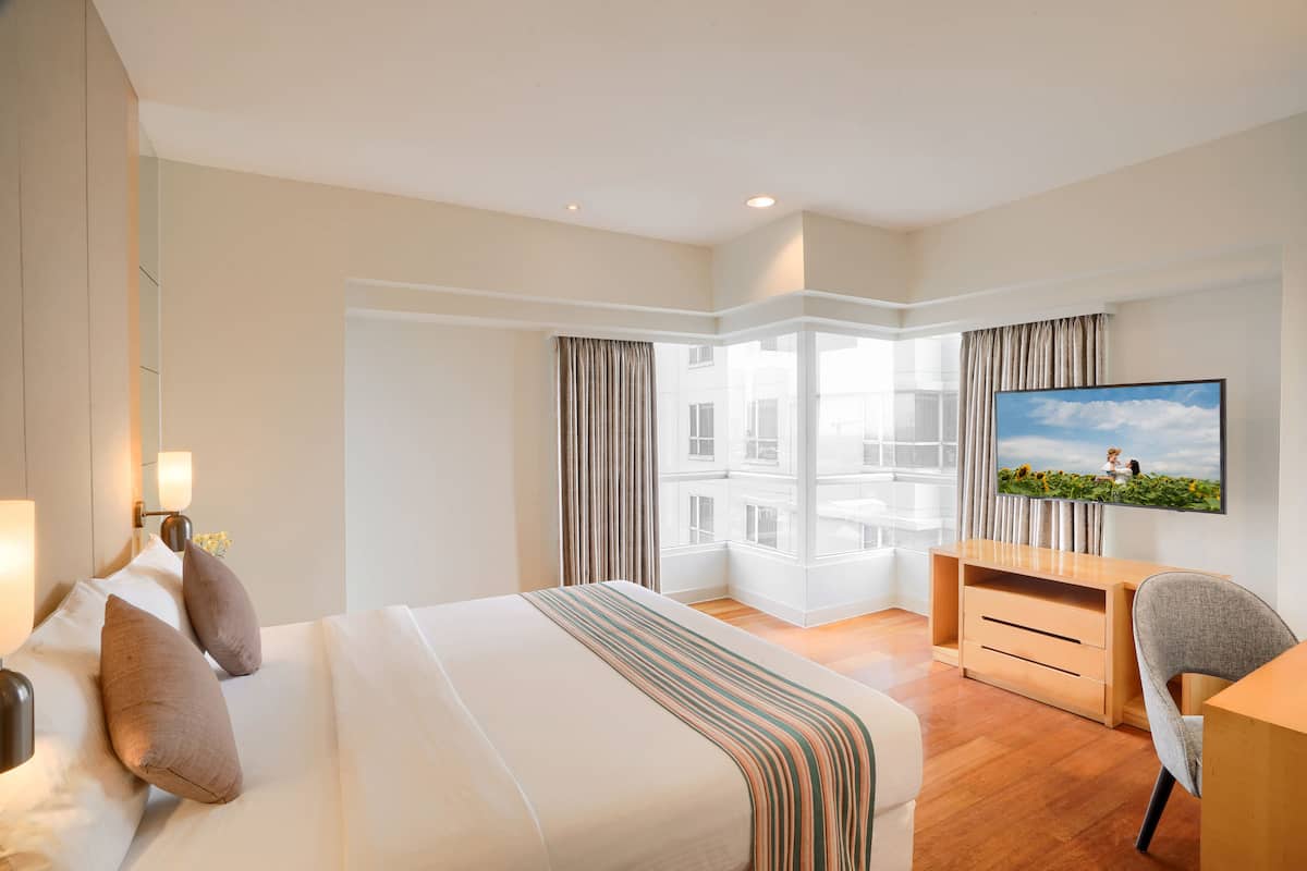 Hotelkamer met een groot bed, een bureau, een stoel, een televisie en uitzicht op een gebouw.