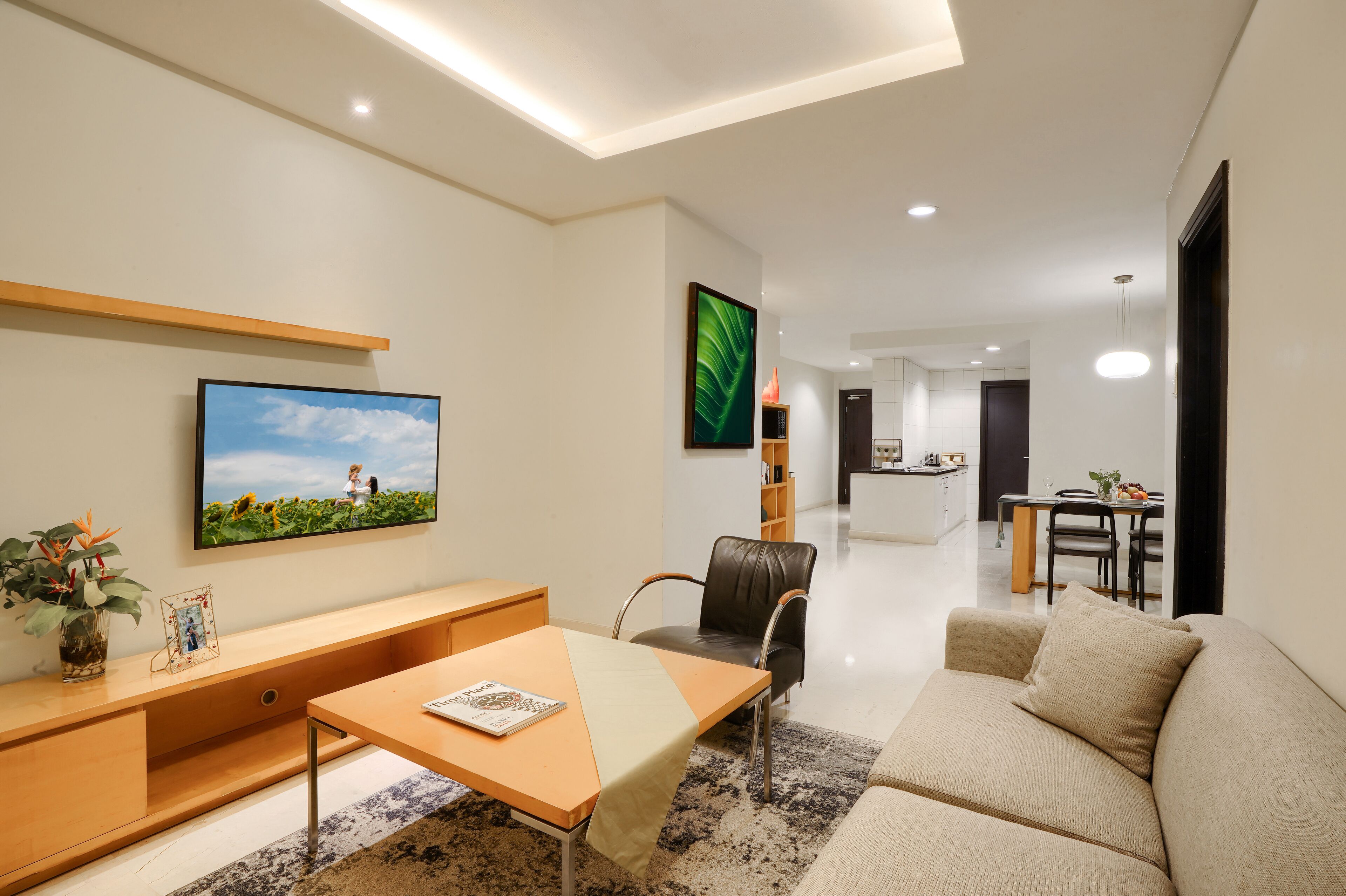 A modern living room with a sofa, a coffee table, a TV, and a bookshelf.