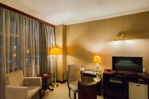 Una habitación de hotel con cama, escritorio con lámpara, televisión y una silla.