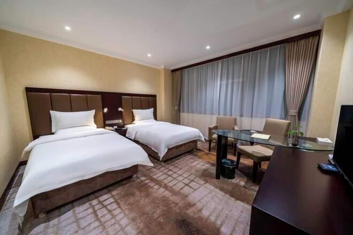 A hotel room with two beds, a desk, and a chair.