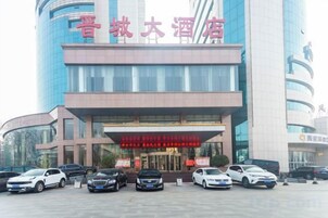 Un hotel con una entrada destacada y varios coches aparcados delante.