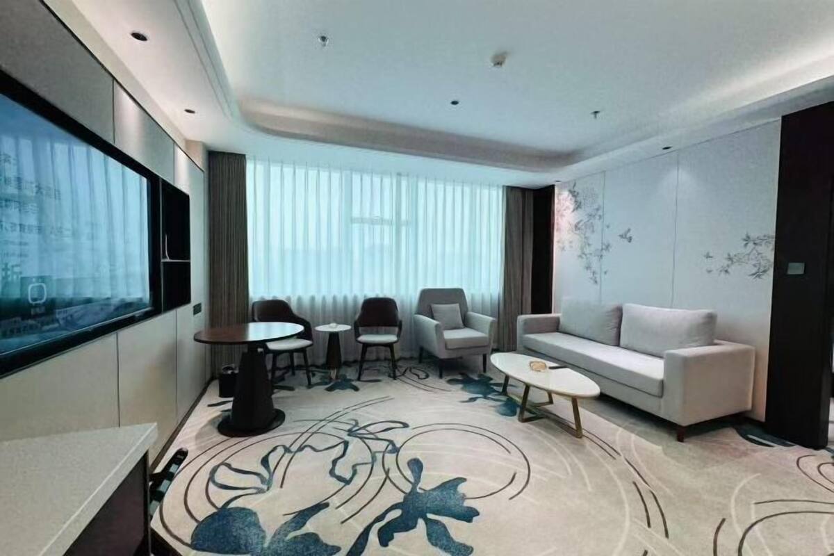 A modern living room with a sofa, armchairs, a coffee table, and a TV.