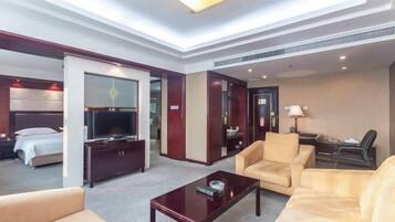 Ein Hotelzimmer mit Bett, Fernseher, Sofa, Couchtisch und Schreibtisch mit Lampe.