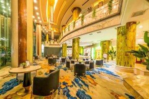 A hotel lobby with a curved ceiling, large columns, and a patterned carpet.