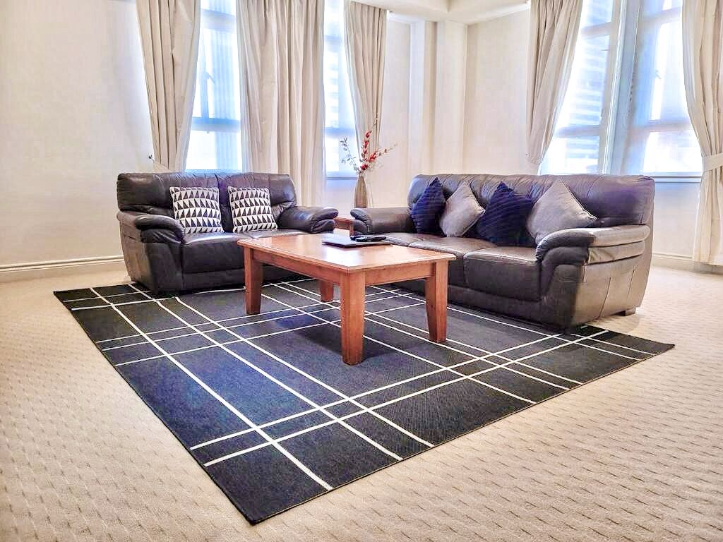A living room with two sofas, a coffee table, and a patterned rug.