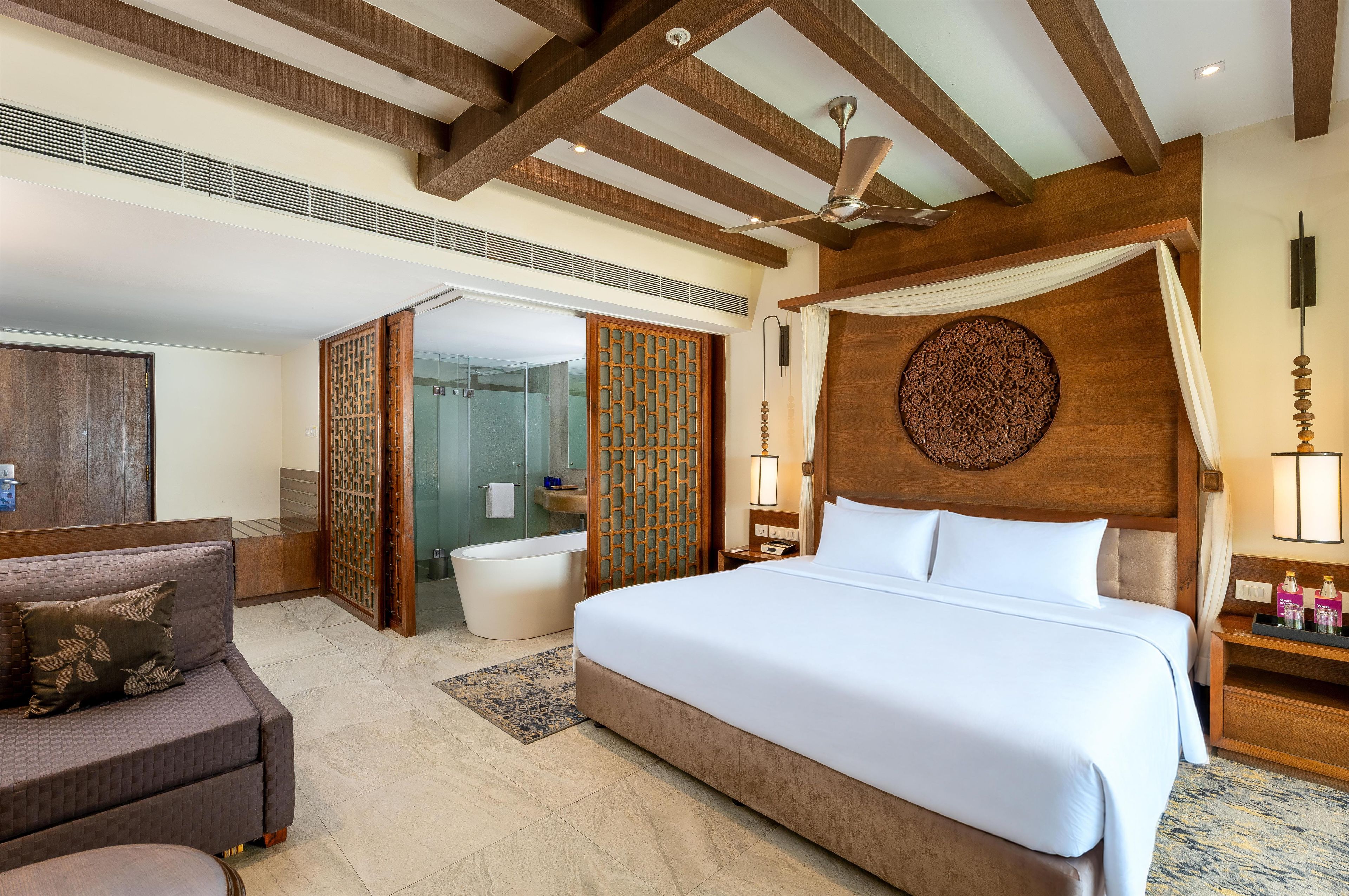 Une chambre d’hôtel dotée d’un grand lit, d’un coin salon, d’une salle de bain et d’un ventilateur de plafond.