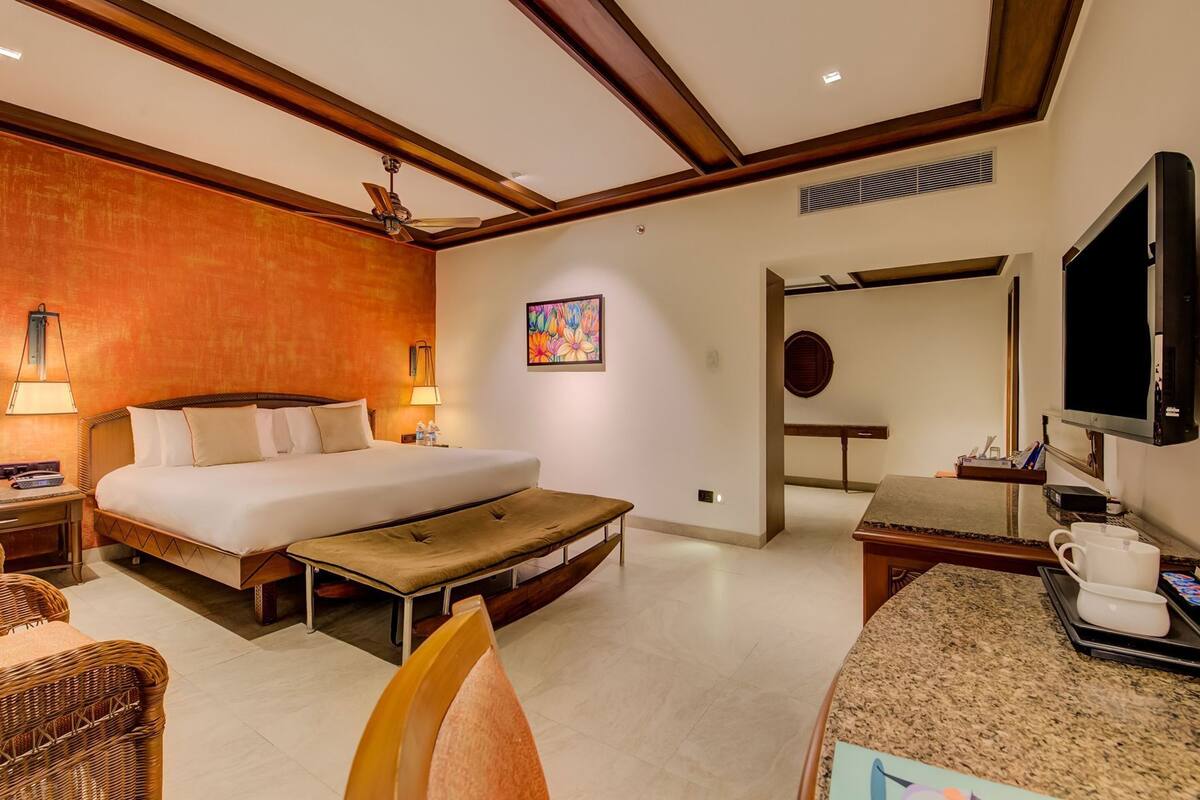 Une chambre d’hôtel comprenant un lit, une table de chevet, une lampe, une télévision et un petit coin salon.