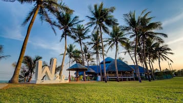 A tropical resort with palm trees, a large 'W' sign, and thatched-roof structures.