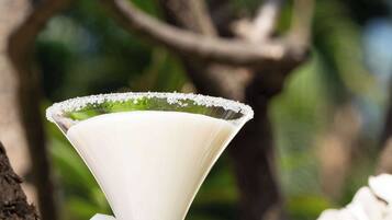 A martini glass with a salted rim, placed on a wooden surface with a blurred natural background.