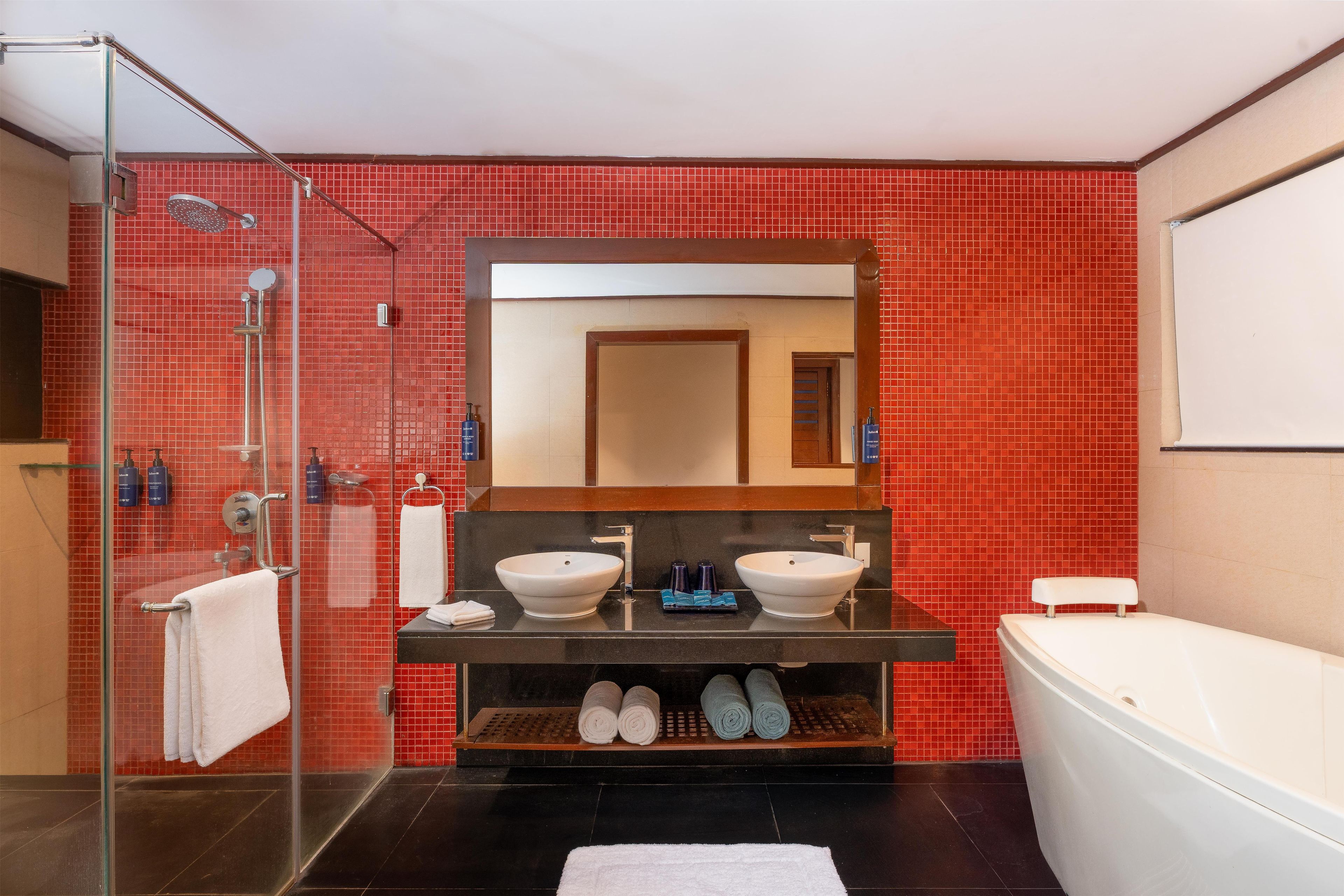 Ein modernes Badezimmer mit Duschkabine aus Glas, einem Doppelwaschtisch und einer freistehenden Badewanne.
