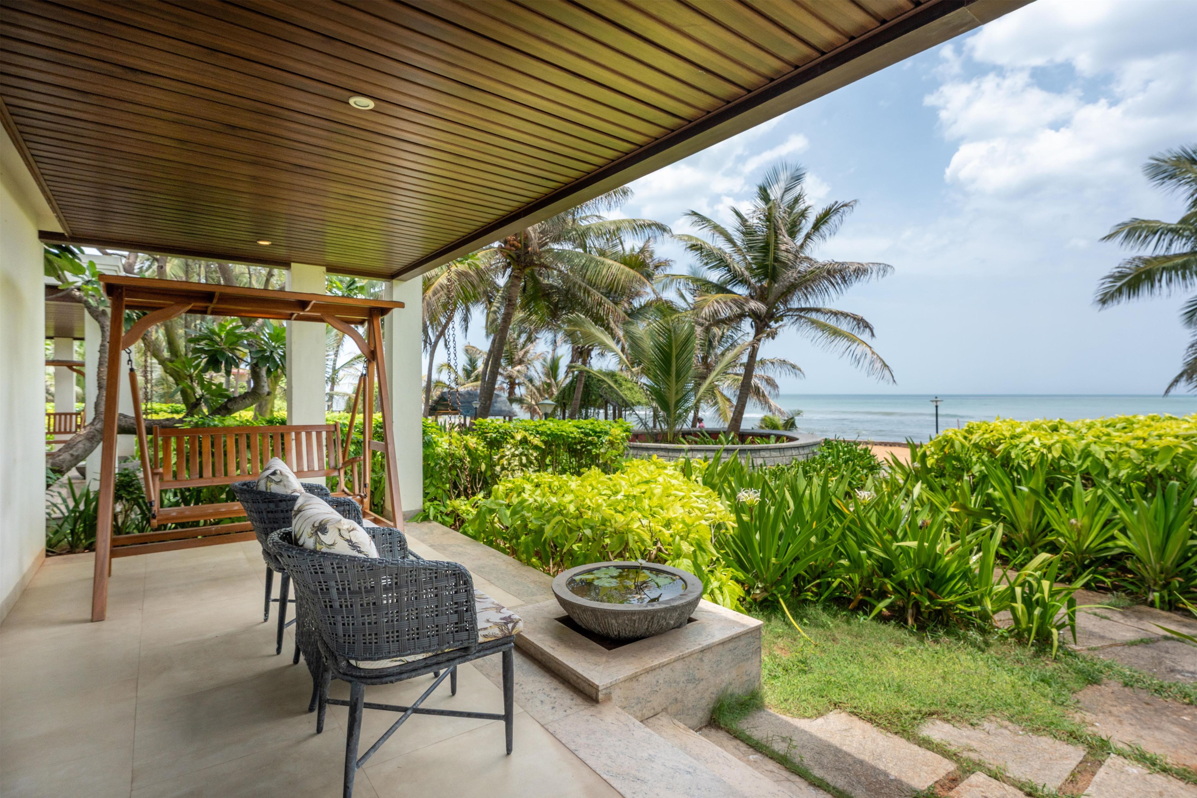 A covered outdoor seating area with wicker furniture and a stone planter.