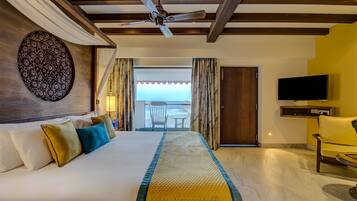 Habitación de hotel con una cama grande, ventilador de techo, televisión y vistas al exterior.
