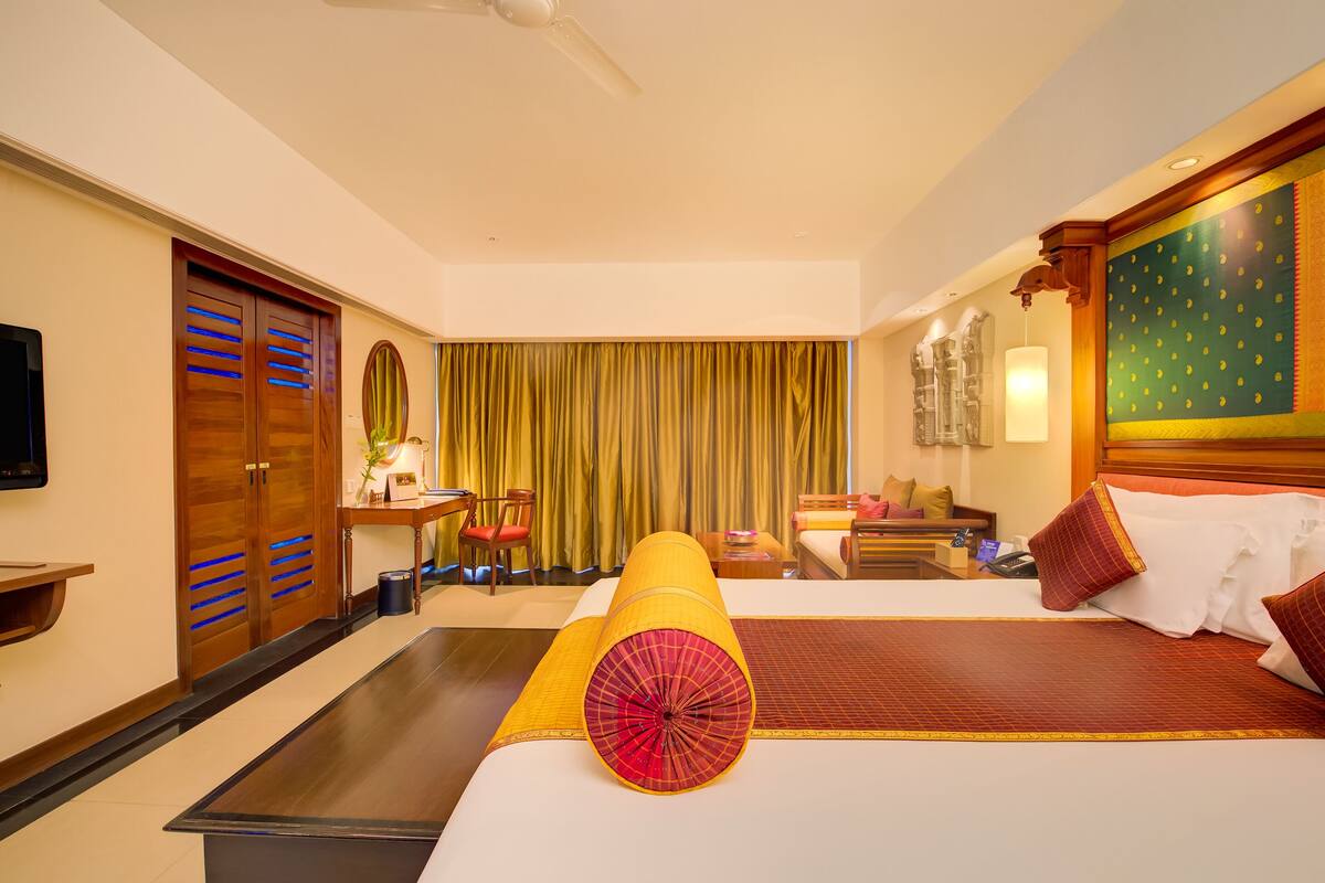Une chambre d’hôtel avec un grand lit, un bureau, une chaise, une télévision et un rideau.