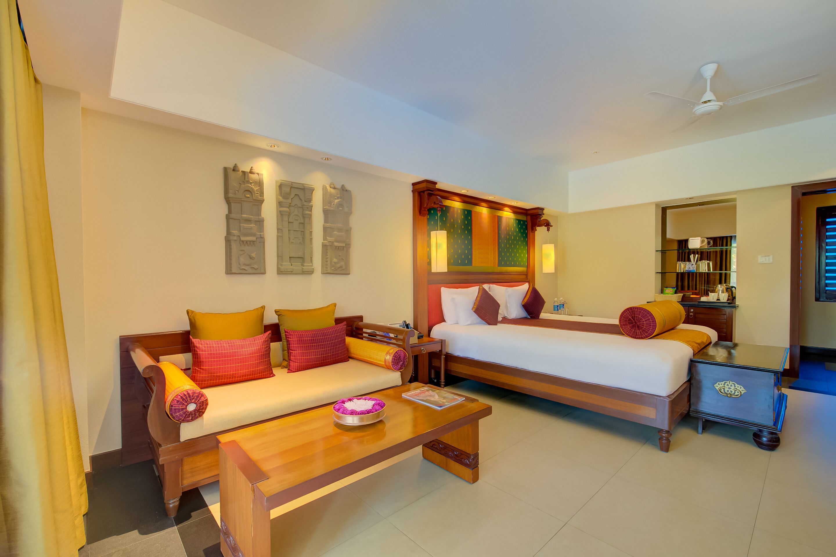 A hotel room with a sofa, a bed, a wooden coffee table, and a nightstand.