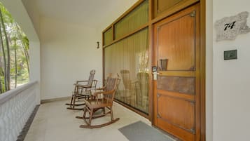 A balcony with a wooden door, a number '74' sign, and a view of the outdoors.