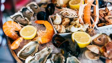 A variety of seafood including shrimp, oysters, and clams on a bed of ice.