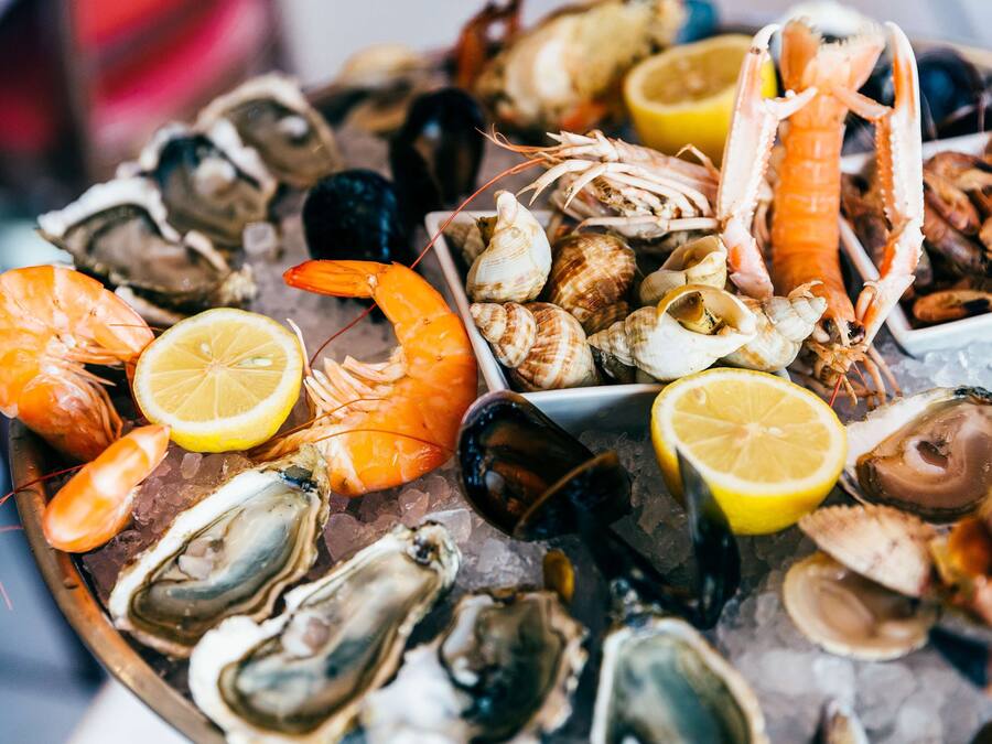 A variety of seafood including shrimp, oysters, and clams on a bed of ice.