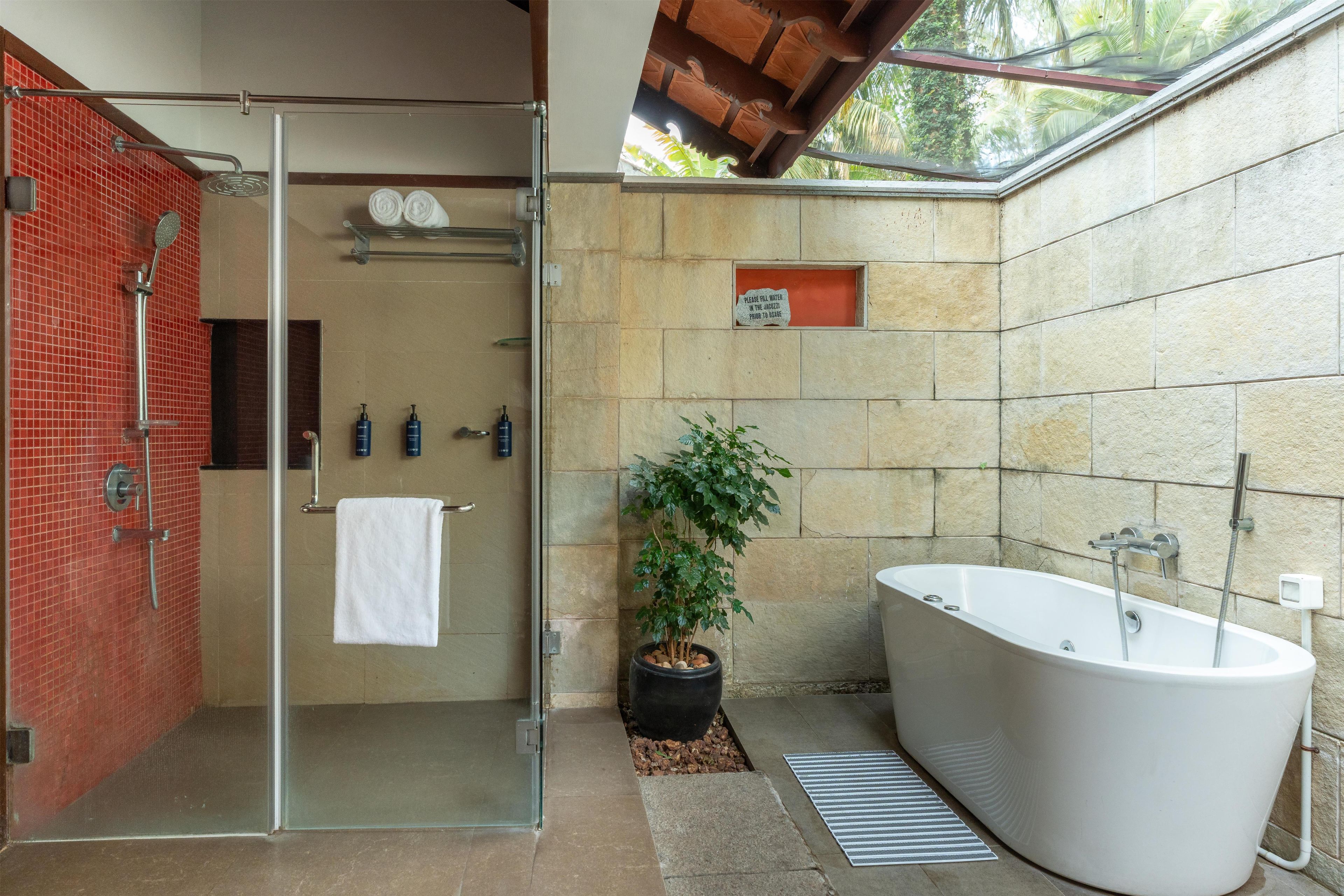 Ein modernes Badezimmer mit einer Glaskabine zur Dusche, einer freistehenden Badewanne und einem Blumentopf.