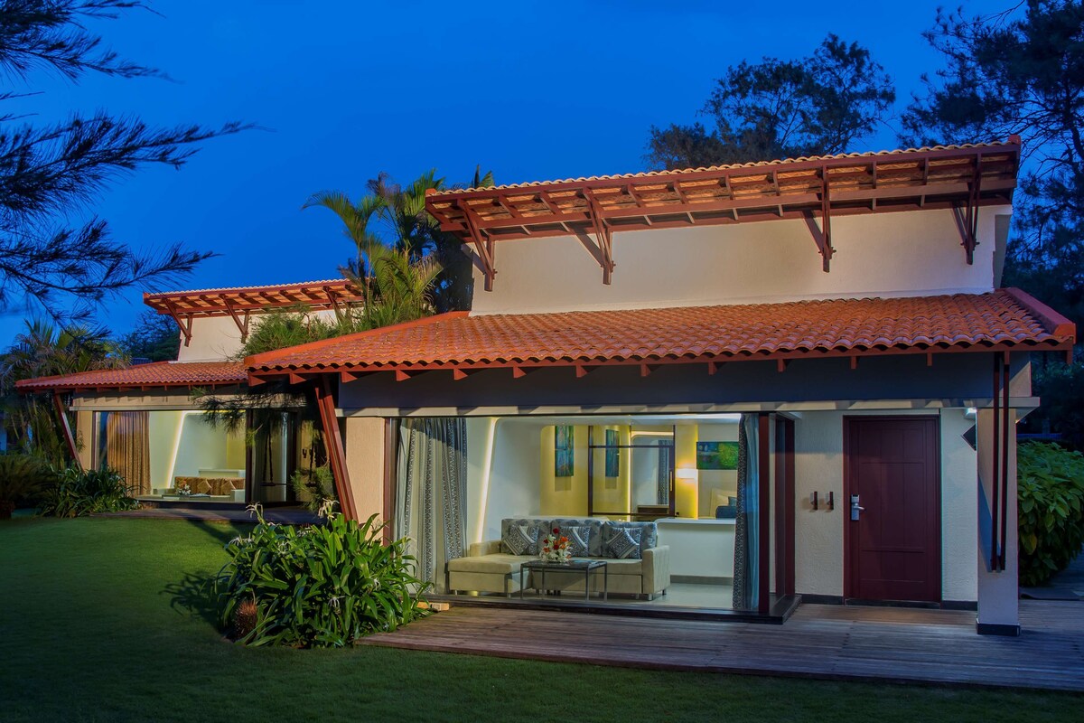A modern two-story house with a patio area, large windows, and a red-tiled roof.