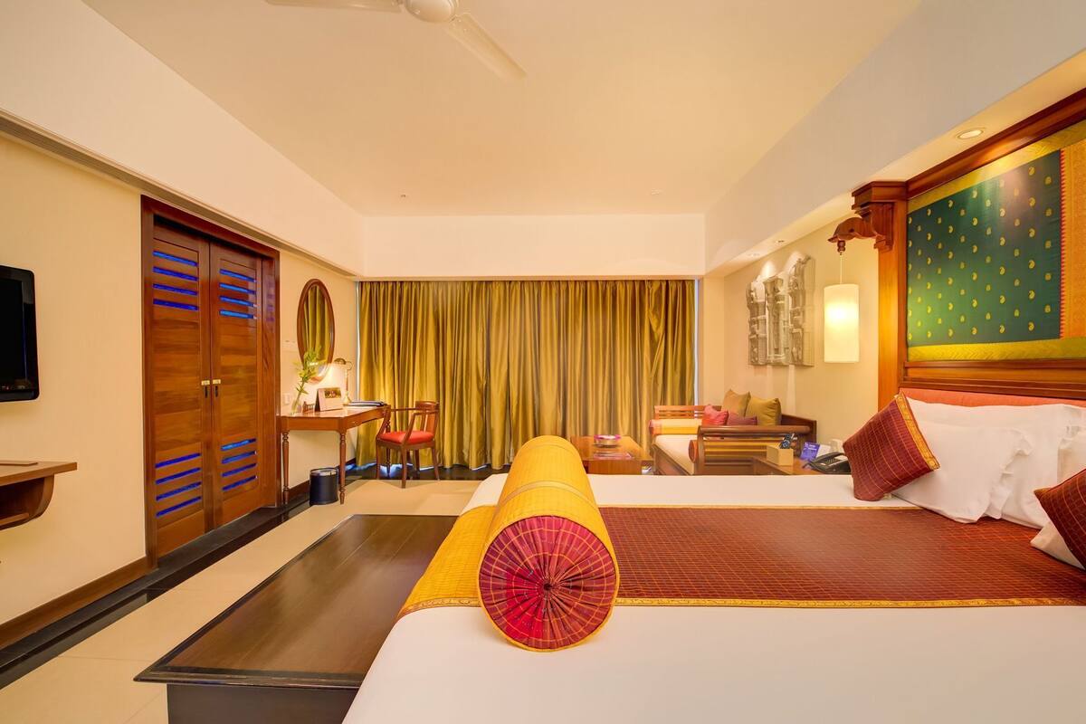 Une chambre d’hôtel avec un lit, un bureau et une chaise, une télévision et une grande fenêtre avec des rideaux.