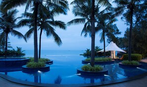 A infinity pool with palm trees and a view of the ocean. - Radisson Blu Resort Temple Bay Mamallapuram (Tirukalukundram)