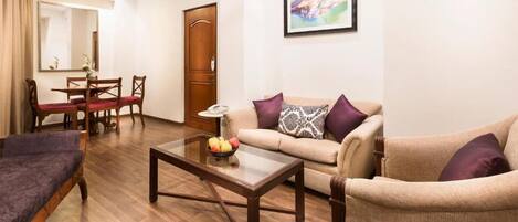 Una sala de estar con sofá, sillón, mesa de centro y un comedor con sillas y mesa.