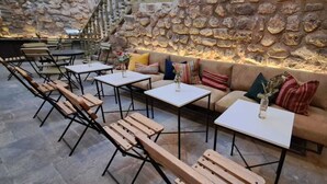 An outdoor seating area with stone walls, wooden benches, and tables. - Sueños del Inka Hotel (Cusco)