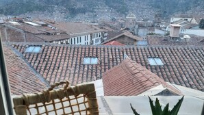 A view from a window overlooking a cityscape with terracotta rooftops and a mountainous backdrop. - Sueños del Inka Hotel (Cusco)